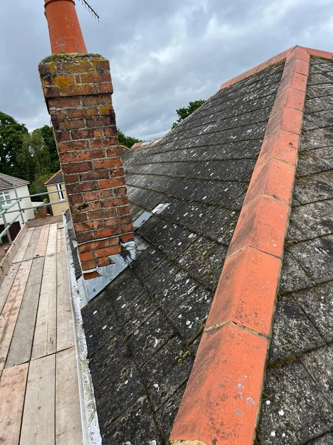 Weathered roof and chimney with worn lead flashing before restoration
