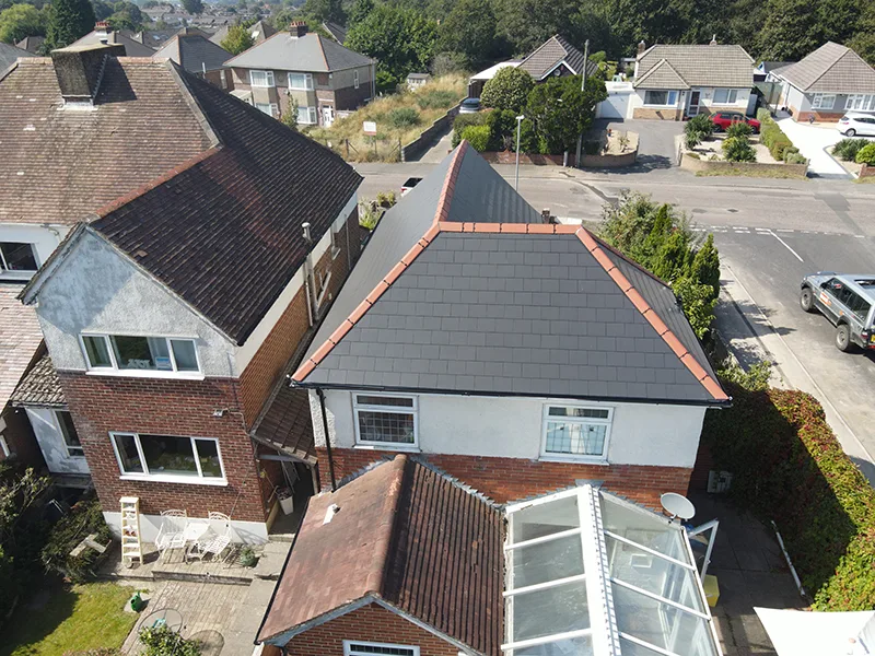 A newly completed tiled roof replacement by KNJ Roofing, next to the older roofs it replaces, Dorset